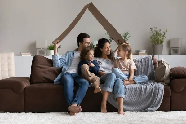 Glada föräldrar och barn leker bostadsspel hemma — Stockfoto