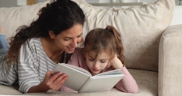 Uvolněný zájem malé předpubertální dítě čtení papírové knihy s matkou. — Stock video
