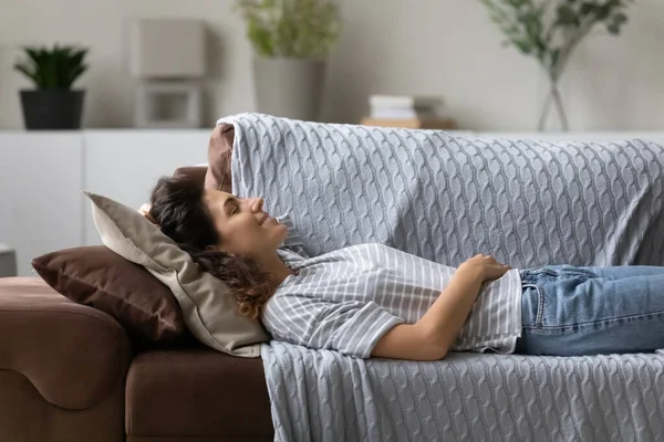 Paisible jeune femme reposant sur un canapé confortable dans le salon — Photo