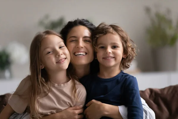 Portret van een gelukkige moeder knuffelen twee leuke kleine kinderen — Stockfoto