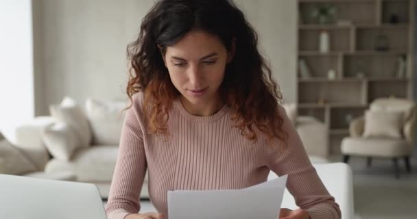 Geconcentreerde slimme jonge zakenvrouw die papieren documenten analyseert. — Stockvideo