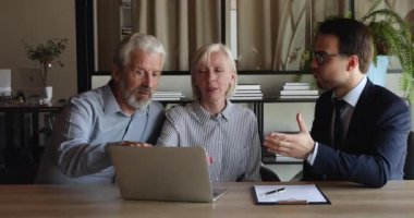 Emlakçı eski müşterilere dizüstü bilgisayarda emlak sunumunu gösteriyor