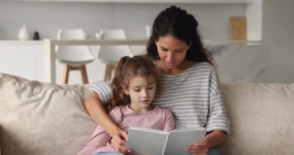 Cuidar a la joven madre feliz leyendo el libro de papel al niño. — Vídeo de stock