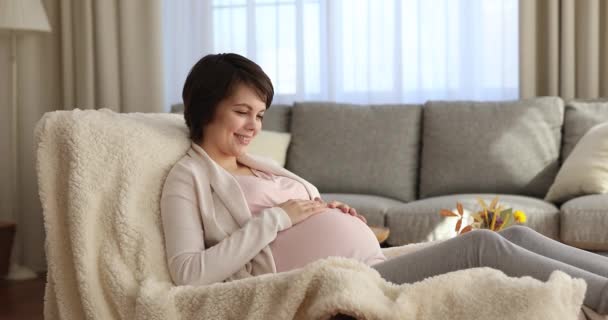 Glücklich inspirierte Millennial schwangere Frau entspannt, streichelt Bauch. — Stockvideo