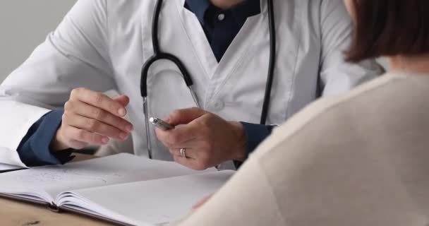 Close up young female doctor consulting older patient. — Stock Video