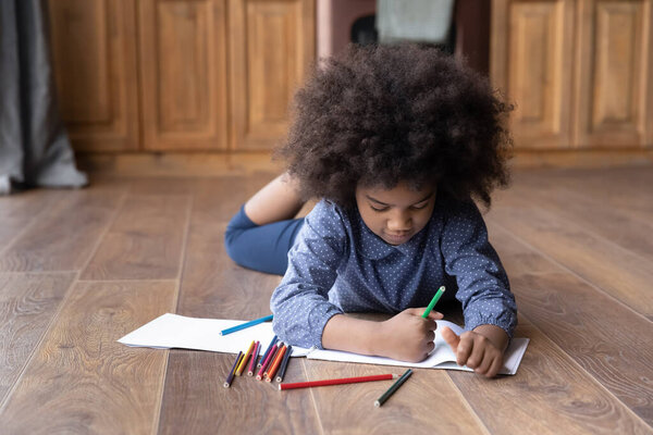 Маленькая девочка-подросток рисует в альбоме дома