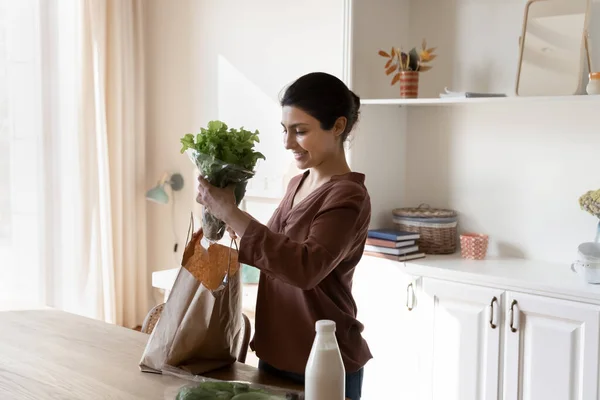 Smiling Indian woman unpack bag with products — Stock Photo, Image