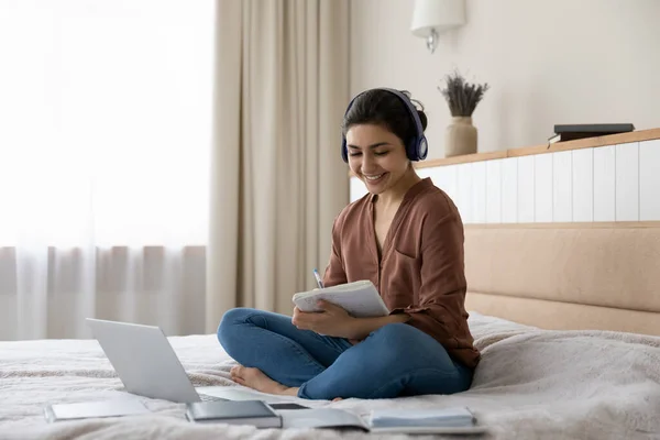 Smiling Indian woman study online on laptop at home