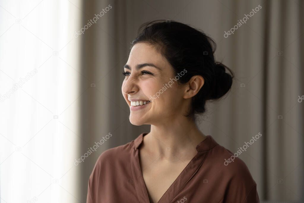 Smiling Indian woman look in distance dreaming