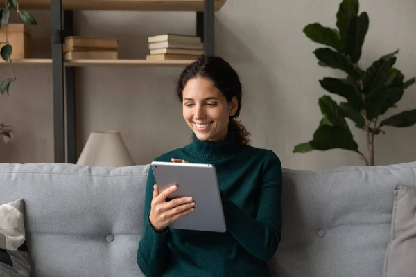 Tablet kullanan, kanepede oturan gülümseyen genç bayanı kapat. — Stok fotoğraf