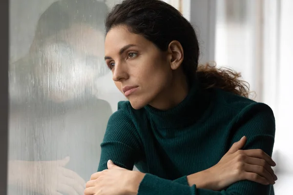 Close up thoughtful upset woman looking in rainy window alone — Stock Photo, Image