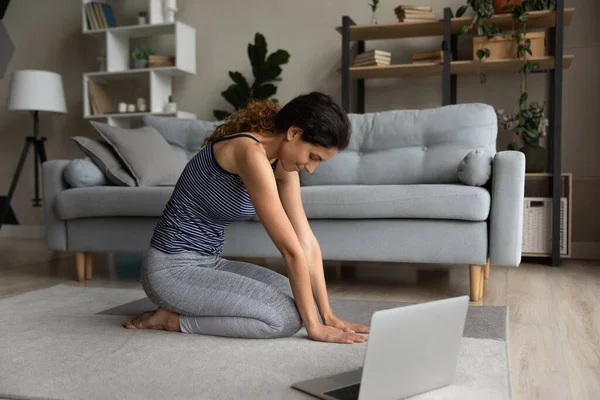 Žena ve sportovním oblečení strečink doma, zapojena do online školení — Stock fotografie