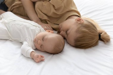 Genç beyaz anne ve yeni doğan bebek yatakta uyur.