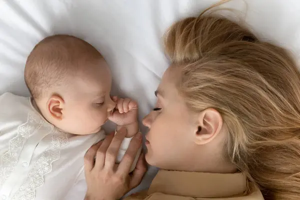 Sevgi dolu anne, bebek bebekle yatakta uyuyor. — Stok fotoğraf