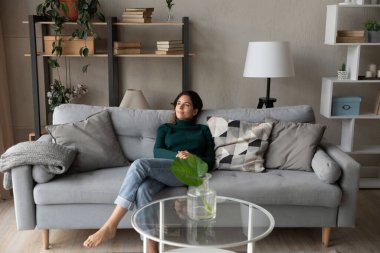 Tatmin olmuş bir kadın modern oturma odasındaki rahat koltukta dinleniyor.