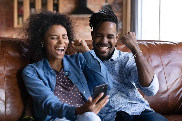 Emocionada pareja birracial triunfo con noticias en el teléfono celular —  Fotos de Stock
