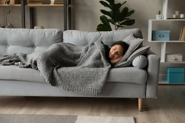 Pełna długość spokojna kobieta spoczywa pod ciepłym kocem na kanapie — Zdjęcie stockowe