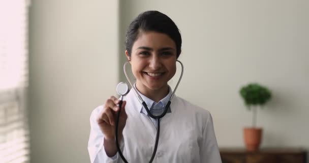 Retrato de tiro na cabeça sorridente indiano feminino médico segurando estetoscópio — Vídeo de Stock