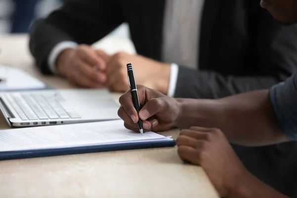 Biracial man ondertekenen document sluiten deal bij vergadering — Stockfoto