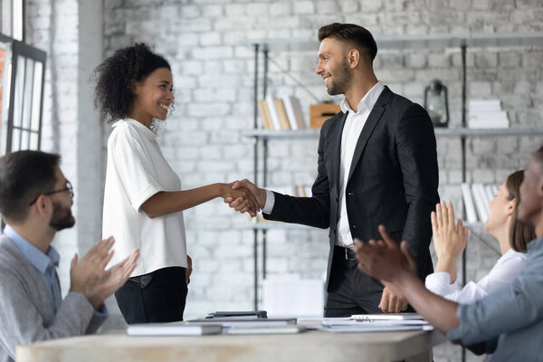 Smiling multiracial businesspeople handshake in office meeting