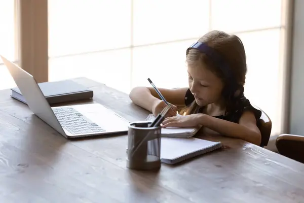 Serieuze kleine gen Z kind in koptelefoon studeren vanuit huis — Stockfoto