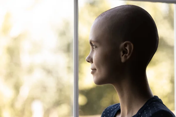 Optimistic cancer woman looking out window with hope