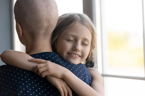 Szczęśliwy córka dziecko obejmując raka mama z zamkniętymi oczami — Zdjęcie stockowe