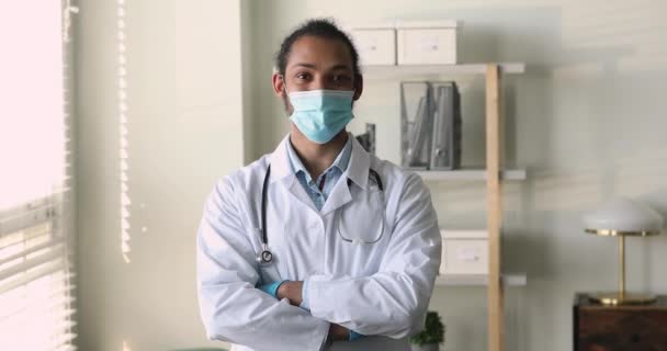 非洲治疗师戴着面具，双手交叉地站在工作场所 — 图库视频影像