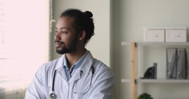 Usmívající se africký terapeut stojí na pracovišti a dívá se z okna — Stock video
