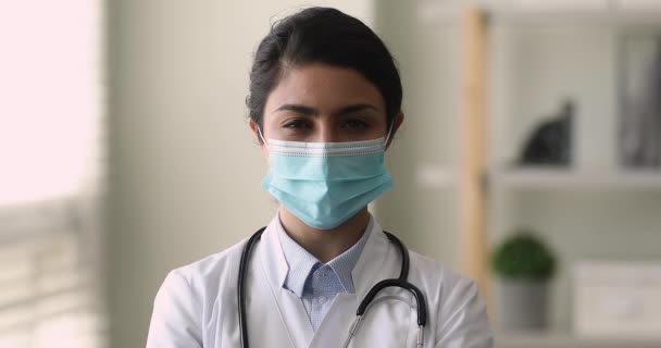 Indiase cardioloog vrouw dragen gezichtsmasker poseren in kliniek kantoor — Stockvideo