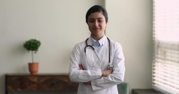 Улыбающийся индийский профессиональный врач носит пальто позировать в офисе клиники — стоковое видео