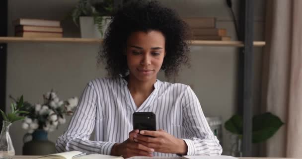 Distrait heureuse femme africaine millénaire jouer téléphone mobile. — Video