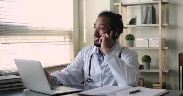 Médico africano proporciona apoyo al cliente de la clínica por llamada telefónica — Vídeos de Stock