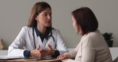 30 'lu yaşlardaki konsantre genç bir doktor yaşlı bir hastaya danışmanlık yapıyor..