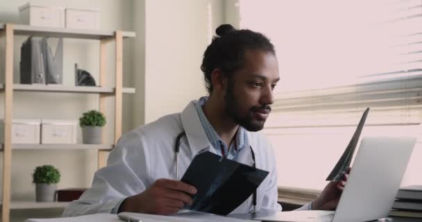 Radiologista africano examina resultados de exames de raios-x em computador portátil — Vídeo de Stock