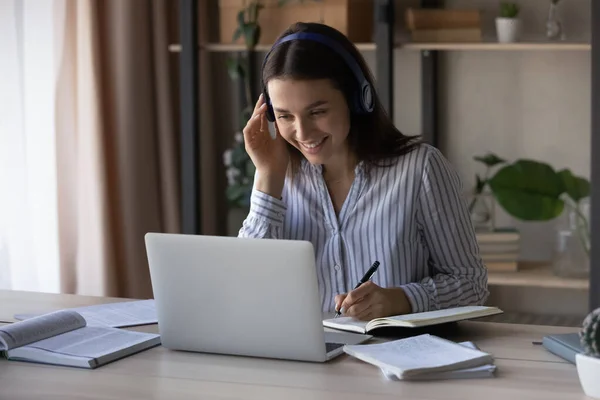 Smiling Caucasian woman in headset study online on computer — стоковое фото