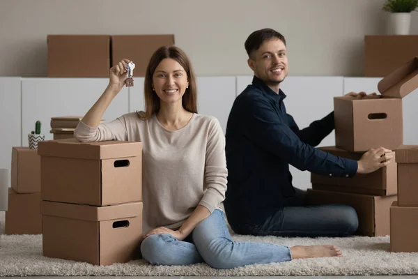 Couple sit on floor near boxes showing keys enjoy relocation — Foto de Stock