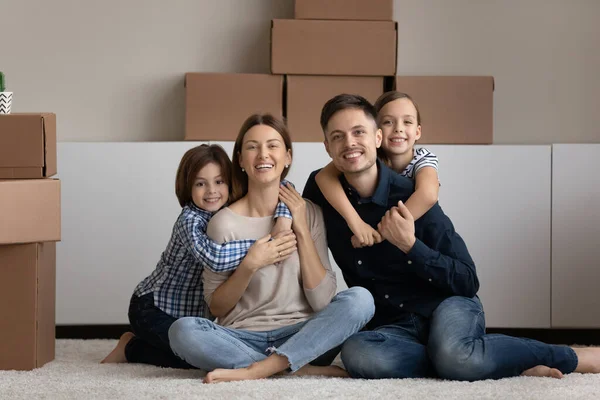 Kids piggyback parents look at camera relaxing on relocation day — Stock Photo, Image