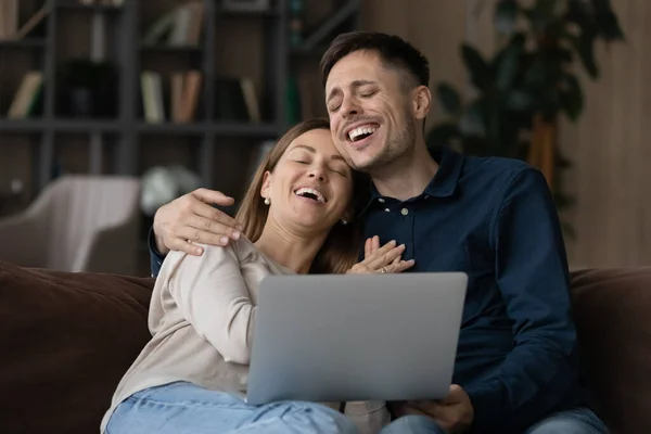 Funny couple sit on couch with computer laughing feel carefree — Foto de Stock