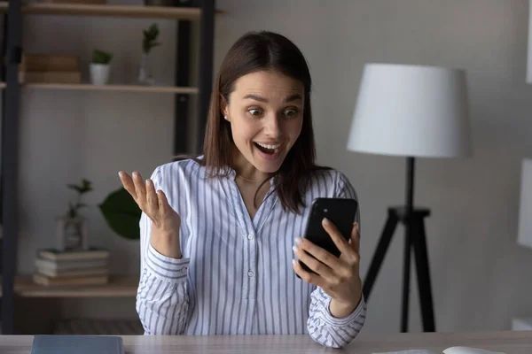 Overjoyed Caucasian woman shocked by good news on smartphone — 图库照片