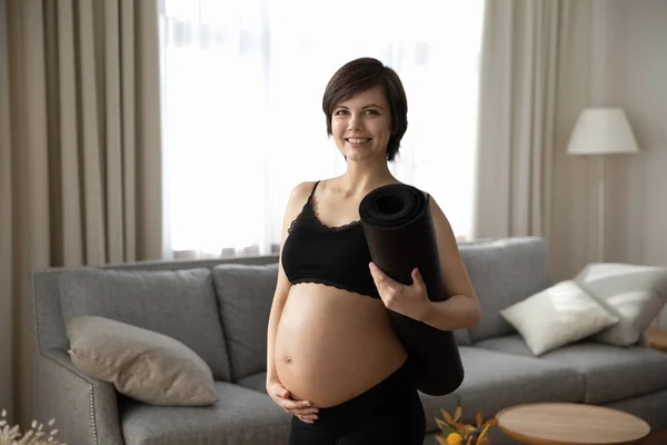 Smiling young pregnant woman ready for home yoga training — Stock fotografie