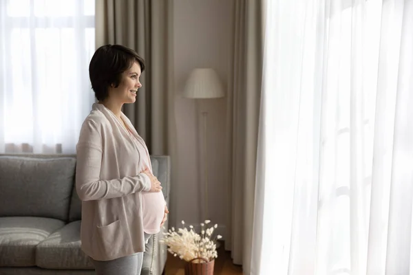 Happy thoughtful expecting mom holding baby bump —  Fotos de Stock