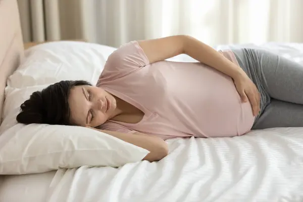 Calm young pregnant woman resting in bed, sleeping peacefully —  Fotos de Stock