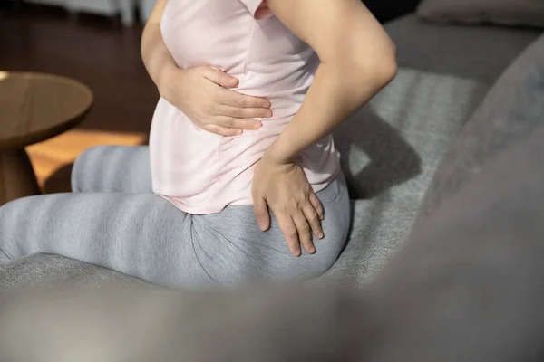 Late pregnant woman suffering from backache, sitting on couch — Fotografia de Stock