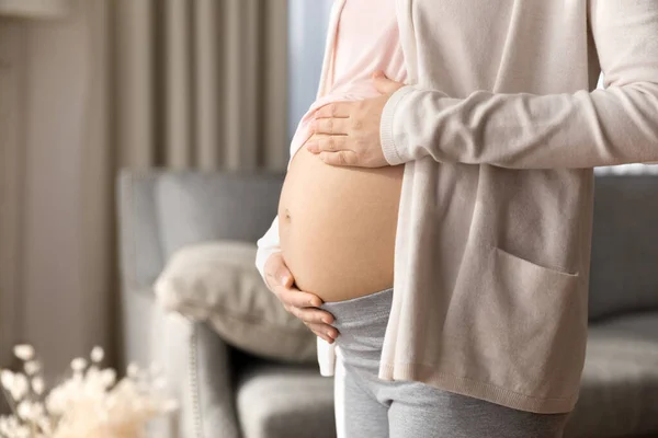 Pregnant woman holding big bare baby bump close up — Photo