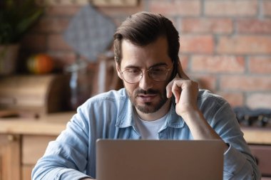 Kafkasyalı işadamı cep telefonuyla dizüstü bilgisayarla konuşuyor.