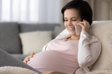 Happy young expecting mom talking on mobile phone