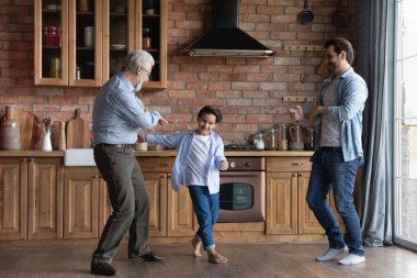 Mutlu üç nesil erkekler evde dans ediyor.