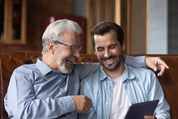 Uśmiechnięty stary tata i dorosły syn używają tabletek w domu — Zdjęcie stockowe