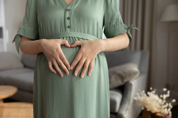 Expecting mom making finger heart on baby bump — Stok fotoğraf